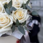 Букет в коробке из белых роз с зеленью.